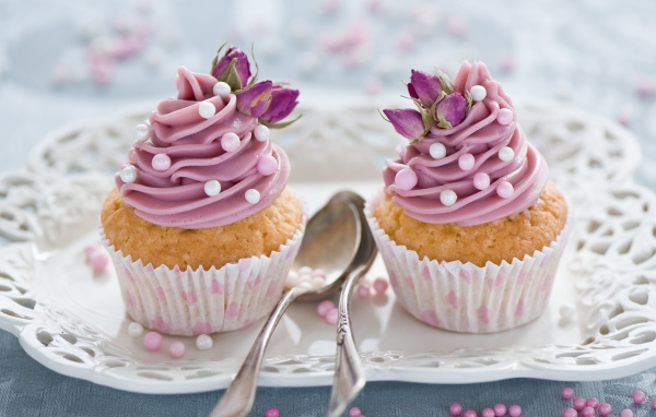 Два вкусных капкейка с кремом на тарелке