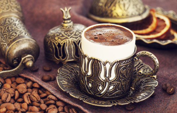 Красивая дизайнерская чашка кофе на столе с зернами