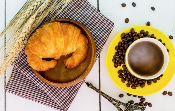 Чашка кофе на столе со свежим круассаном