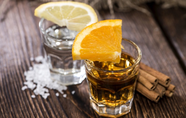 Рюмка водки и рюмка виски на столе с кусочками лимона