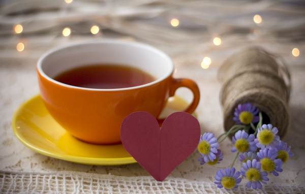 Большая чашка чая на столе с розовым бумажным сердцем и цветами