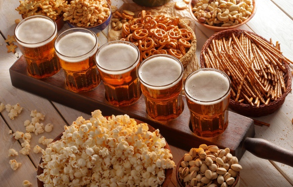 Пиво с орешками, фисташками, попкорном и печеньем на столе