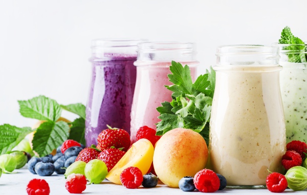 Ягодные смузи в бутылочках на столе с ягодами