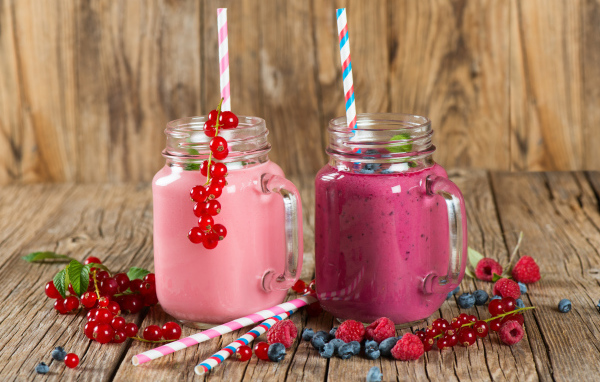Ягодное смузи в баночках на столе со свежими ягодами малины, смородины и черники