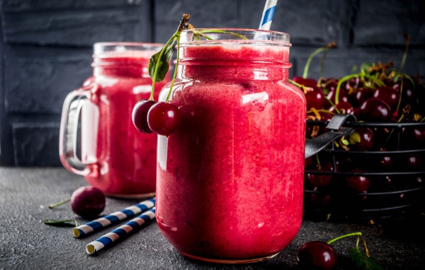 Вишневое смузи в стеклянной банке на столе с ягодами