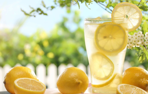 Холодный лимонад в стакане с кусочками лимона