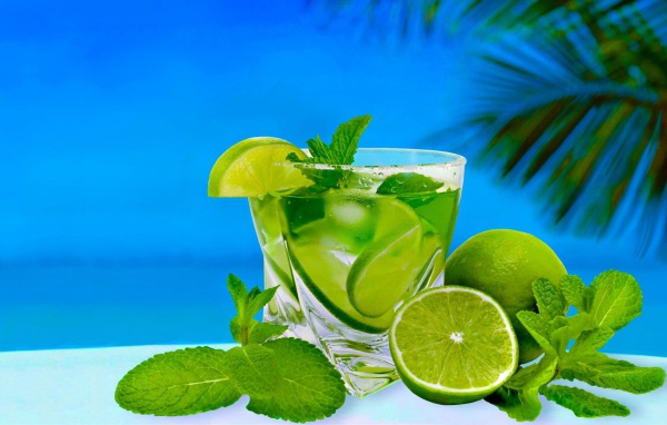 Мохито в стакане со свежей мятой и лаймом на тропическом пляже