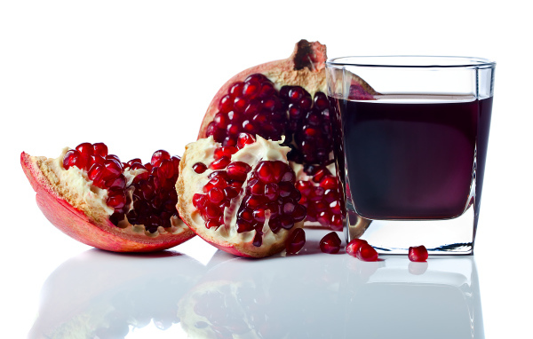Гранатовый сок с плодом граната на белом фоне