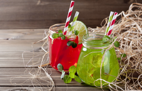 Две банки с коктейлями на деревянном столе с соломой