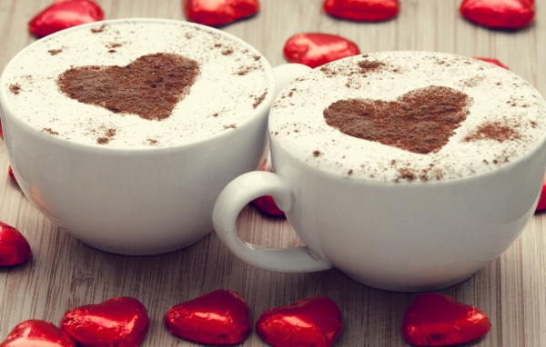 Две чашки кофе на столе с шоколадными конфетами в форме сердца