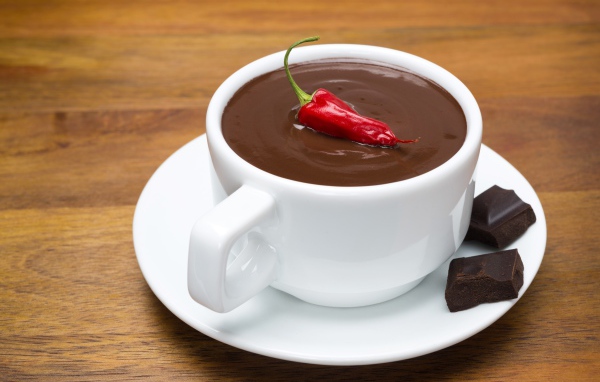 Белая чашка горячего шоколада с красным перцем