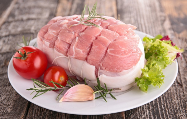 Кусок свежего мяса со свежими помидорами, чесноком и листьями салата