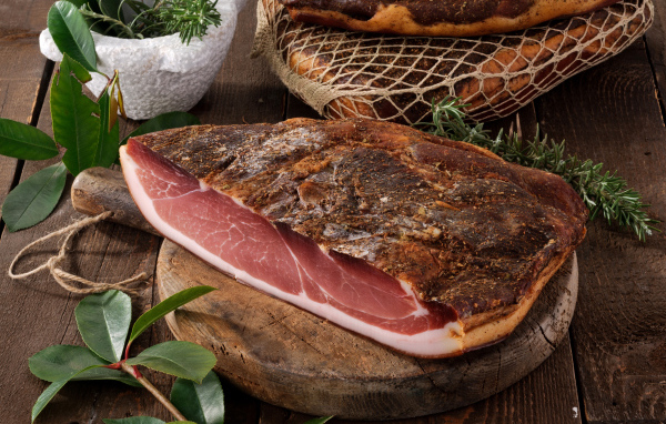 Кусок копченого мяса со специями на разделочной доске