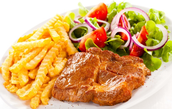 Appetizing chop on a plate with french fries and salad