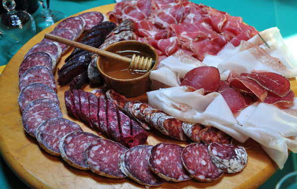 Аппетитная мясная нарезка на разделочной доске с медом