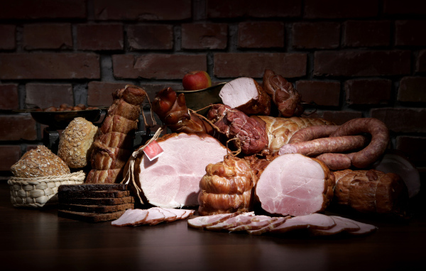 Аппетитные мясные продукты на фоне кирпичной стены 