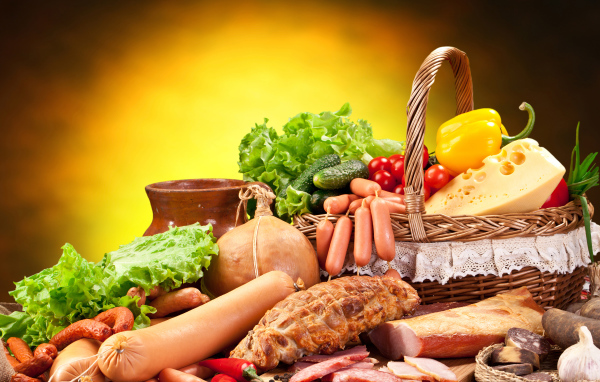 Аппетитные мясные продукты на столе с корзиной овощей