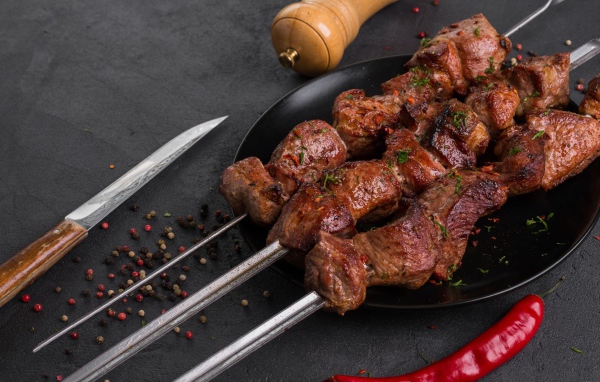 Аппетитный мясной шашлык на столе с перцем 