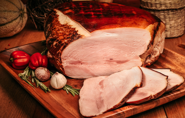 Аппетитный кусок ветчины с перцем и чесноком на доске