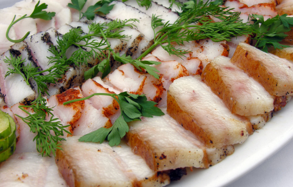 Аппетитное нарезанное копченое сало с зеленью 