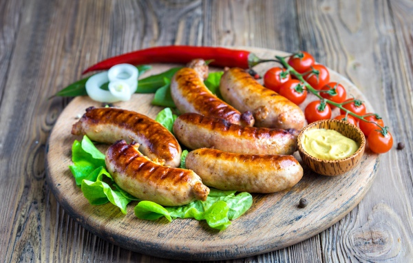 Сосиски барбекю с красным перцем и помидорами на разделочной доске