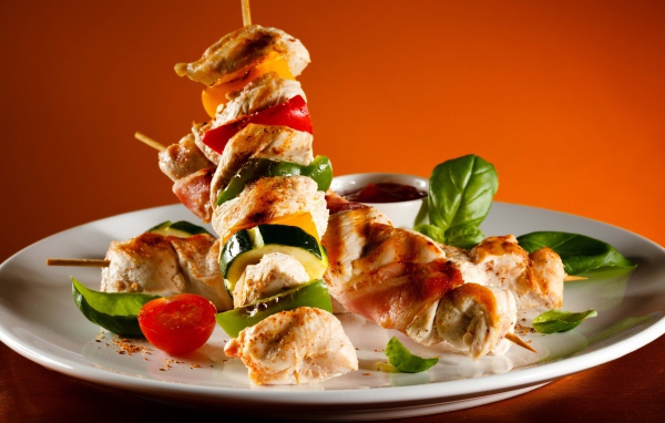 Куриные шашлыки с овощами на белой тарелке