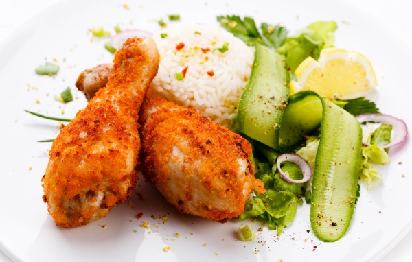 Куриные ножки с рисом и салатом на белой тарелке