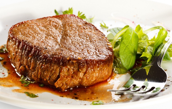 Отбивная с зеленым салатом на тарелке с вилкой