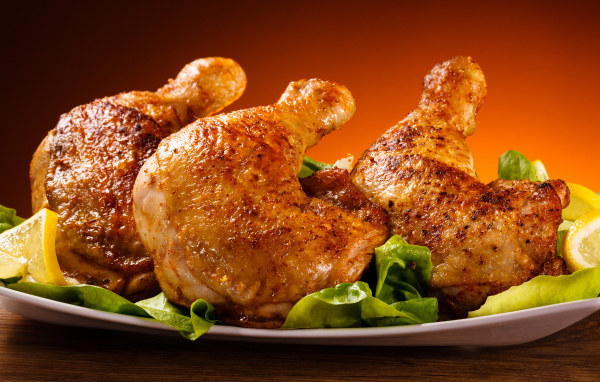 Жареные куриные окорочка на зеленых листьях салата 