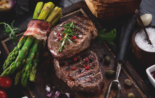 Жареное мясо с зеленой спаржей на столе 