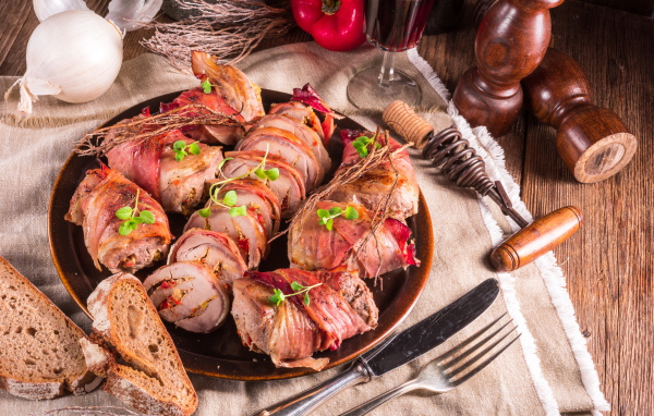 Нарезанные мясные рулеты на столе с хлебом