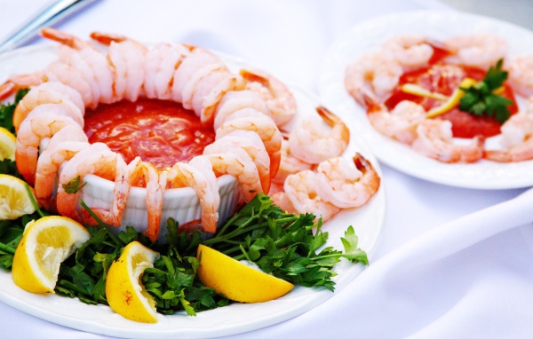 Boiled shrimps with sauce on a plate with lemon and parsley