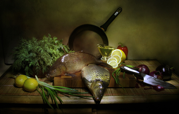 Сырая рыба на столе с зеленью, лимонами и луком 