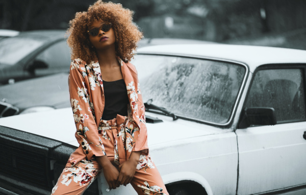 Красивая темнокожая девушка сидит на автомобиле 