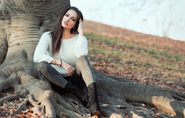 Красивая девушка сидит у дерева