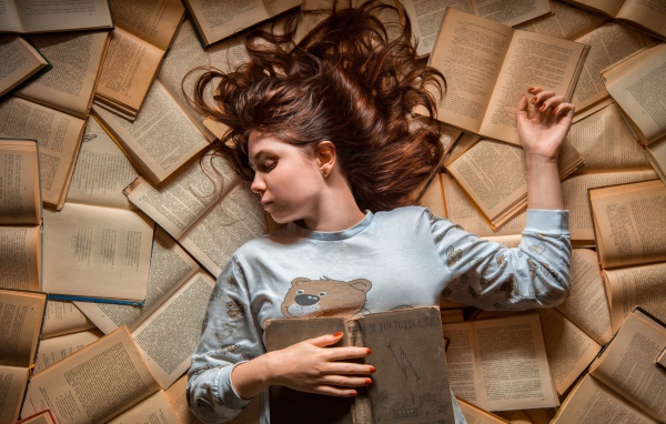 Молодая девушка спит на книгах