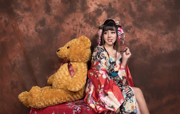 Девушка азиатка сидит с большим плюшевым медведем