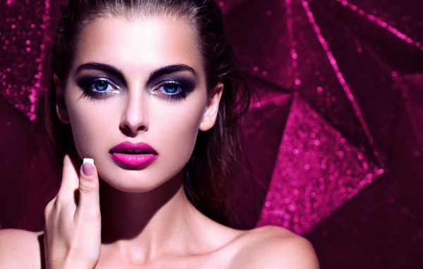 Красивая голубоглазая брюнетка с макияжем на сиреневом фоне