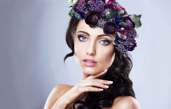 Красивая голубоглазая девушка с венком на голове на сером фоне
