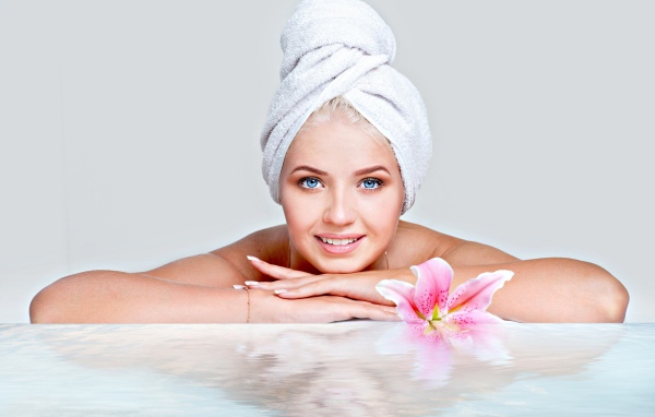 Красивая голубоглазая женщина в тюрбане с полотенца расслабляется в SPA