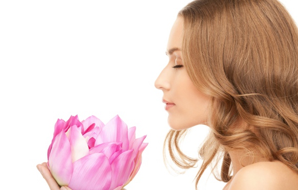 Красивая девушка шатенка наслаждается ароматом лотоса 