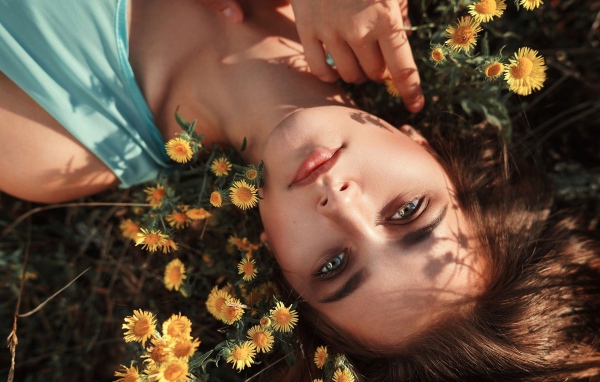 Красивая шатенка лежит на земле с желтыми цветами