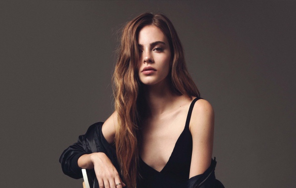 Красивая брюнетка в черном платье сидит на стуле