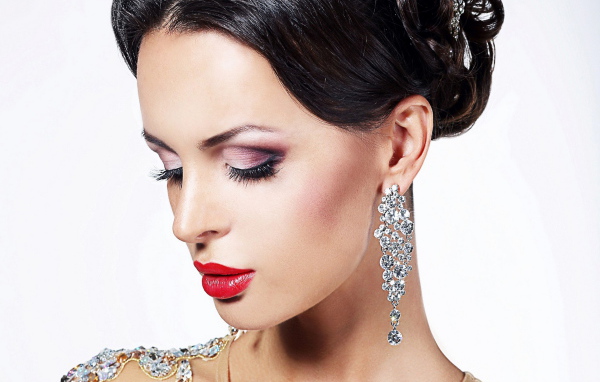 Красивая брюнетка в дорогих украшениях на белом фоне