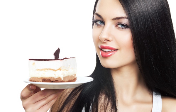 Красивая брюнетка с куском торта на блюдце