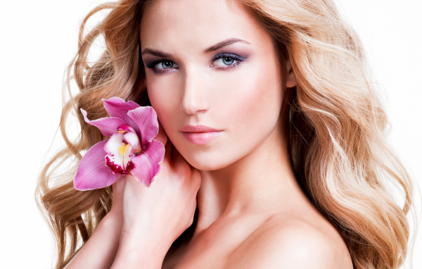 Красивая нежная блондинка с цветком орхидеи на белом фоне