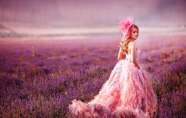 Красивая девушка в розовом платье гуляет по лавандовому полю