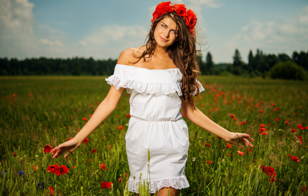 Красивая девушка в белом платье с венком из красных маков на голове 