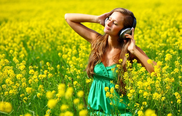 Красивая девушка в наушниках среди желтых цветов