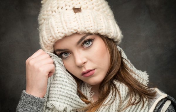Красивая зеленоглазая девушка в белой вязаной шапке с шарфом